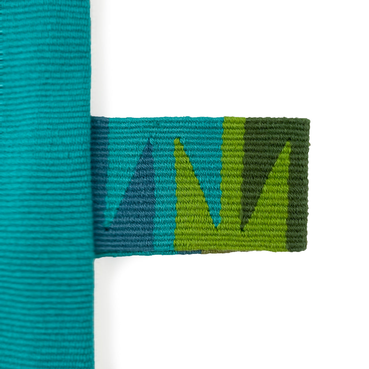 Closeup of handwoven cinta tag in turquoise, teal, and shades of green