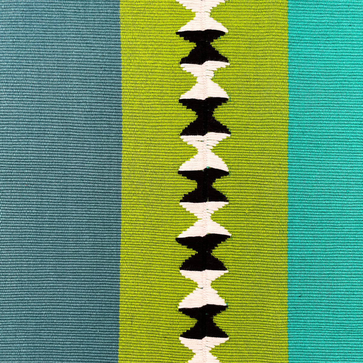 Close up swatch of cushion cover with color block panels in turquoise, green with black and white randa detail, and teal