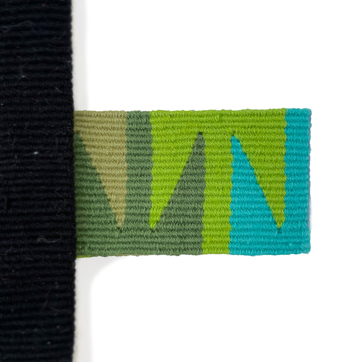 Closeup of handwoven cinta tag with green tones