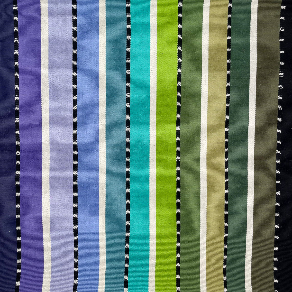 Closeup swatch of cushion cover with colorful stripes grading from purple, blue, teal, green, to black