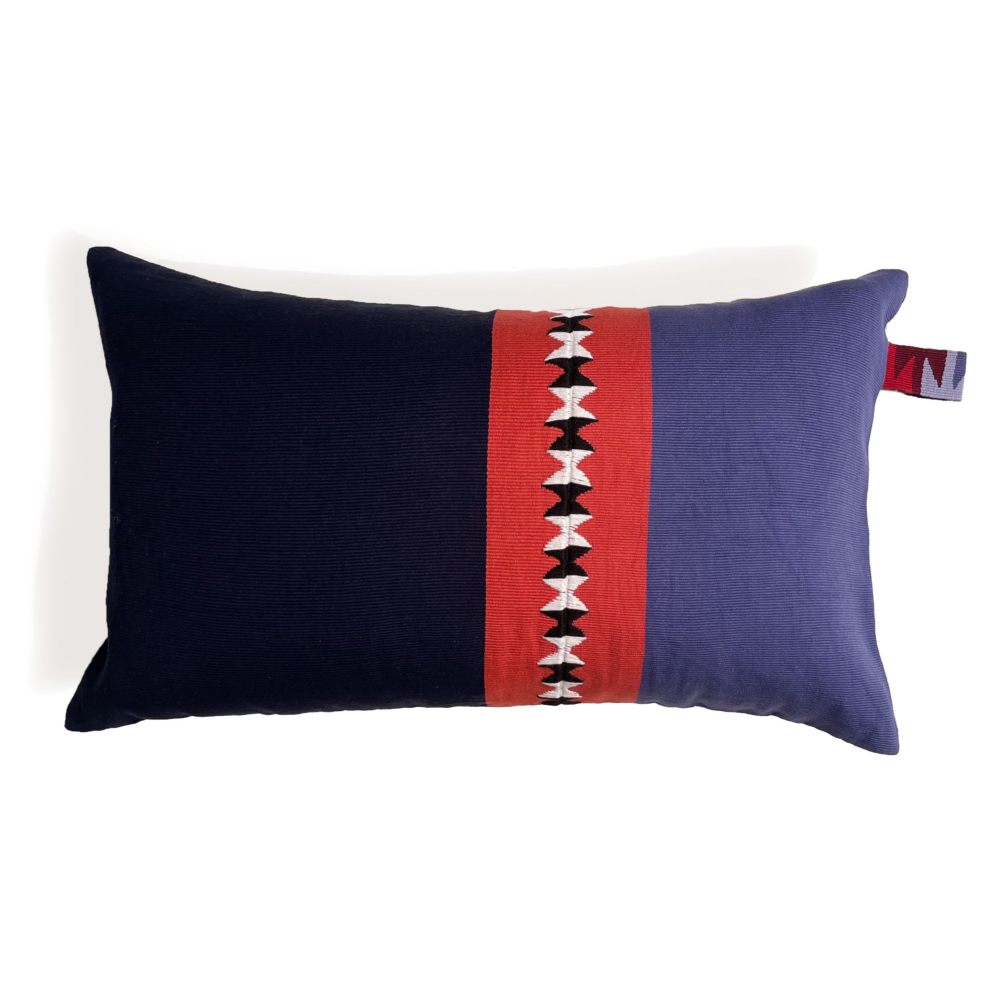 Front of rectangular cushion with color block panels in navy, red with black and white randa detail, and purple, with colorful cinta tag