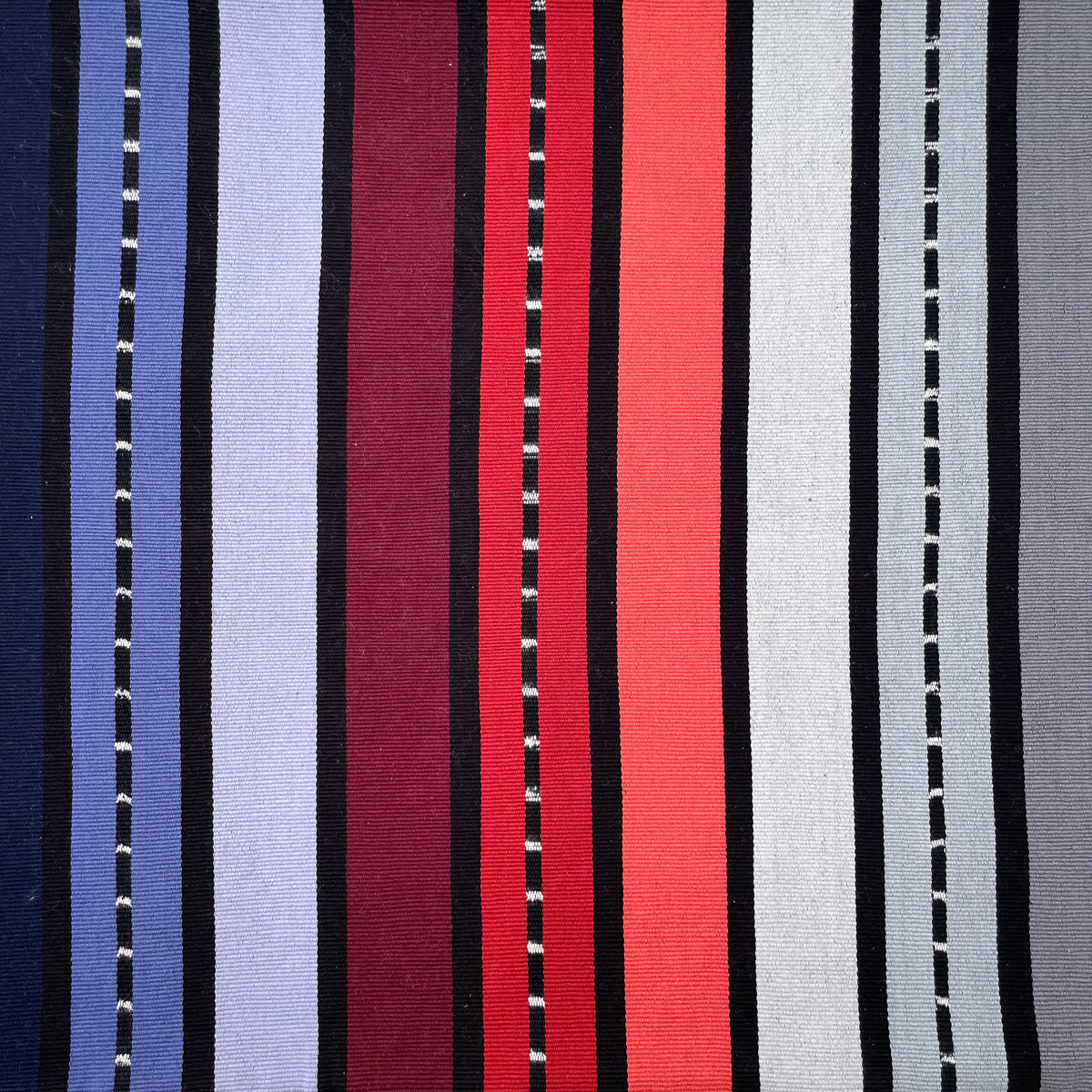Closeup swatch of cushion cover with colorful stripes grading from black, purple, red, to grey, with accent stripes in black and white jaspe