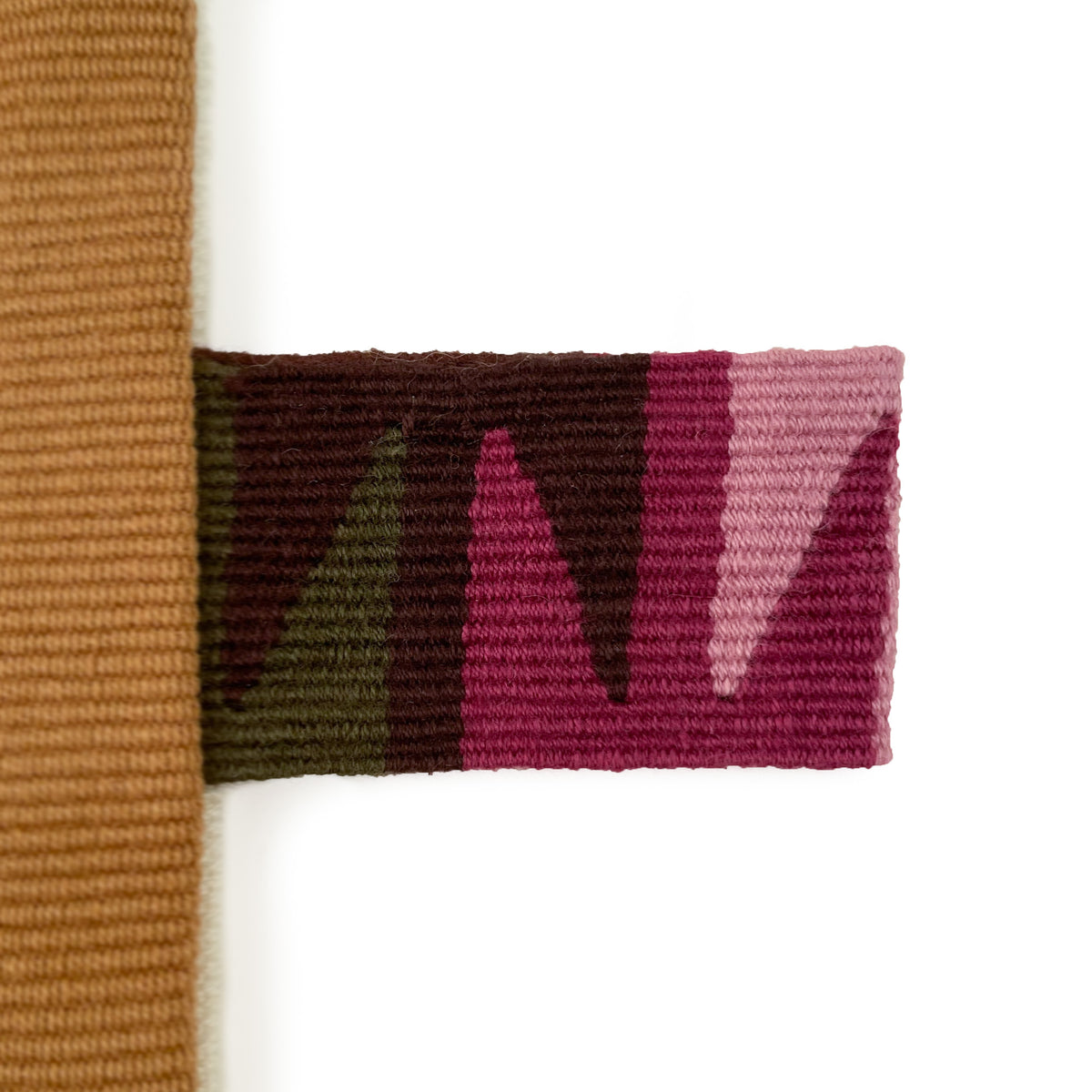 Closeup of handwoven cinta tag in green, brown, and shades of pink