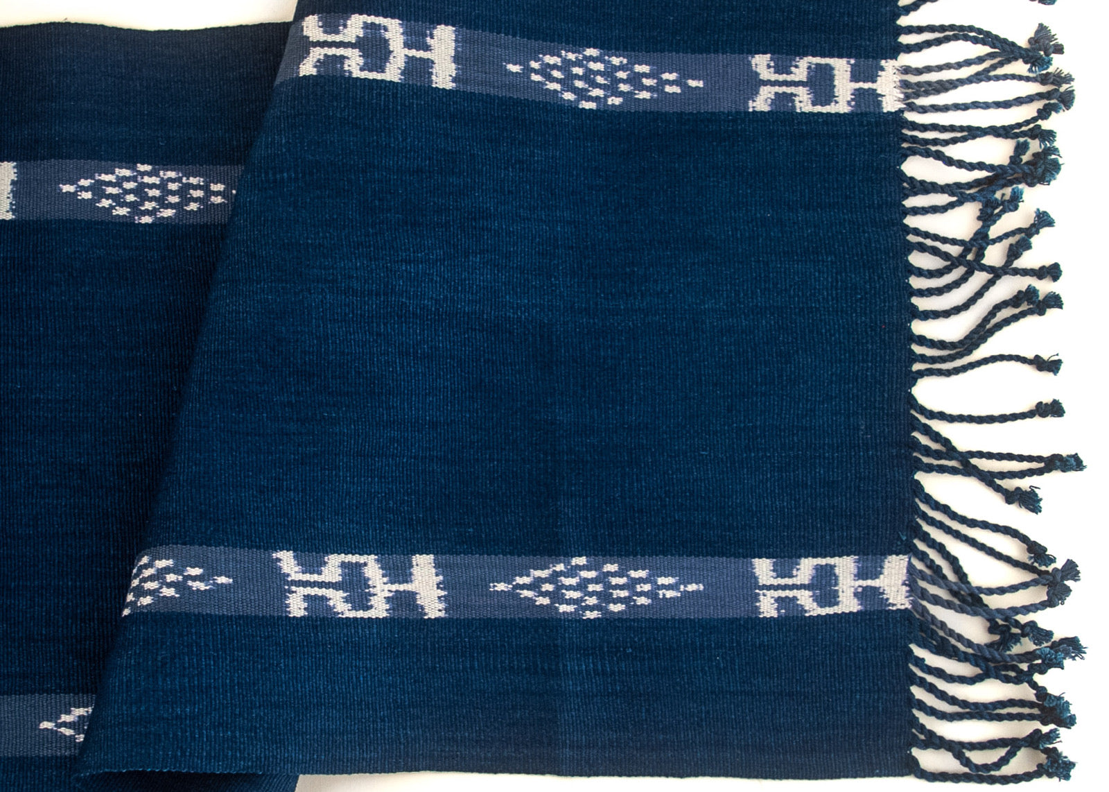 Close-up image of an indigo blue textile featuring Jaspe ikat geometric designs