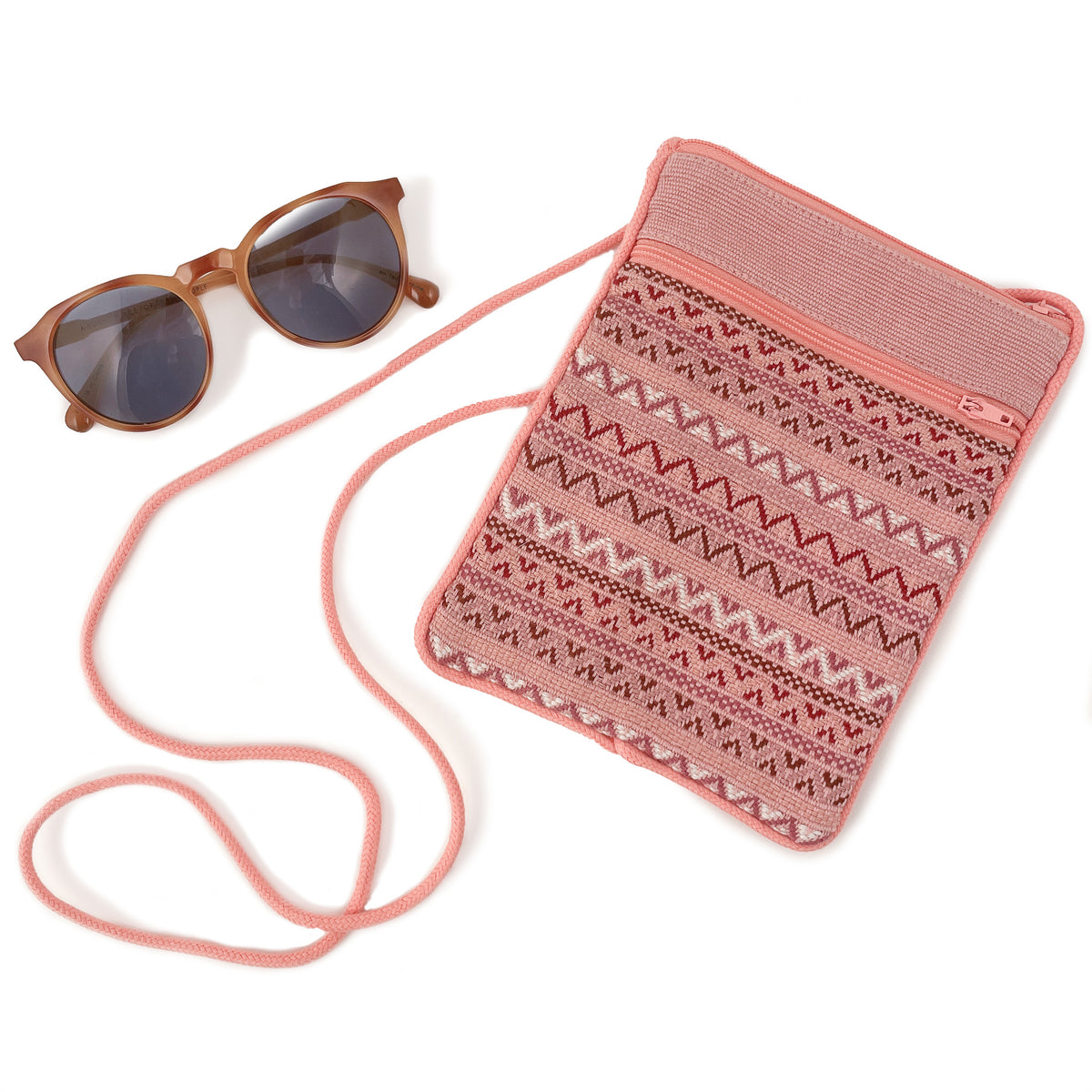 Flat lay photo of blush brocade pocket bag next to a pair of sunglasses