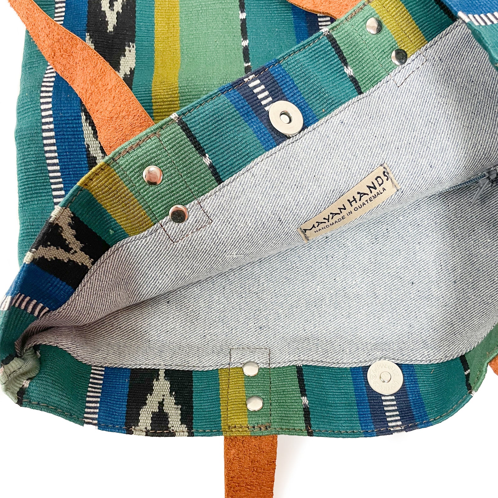 Front view of Matea Bag in Green Jaspe, featuring traditional jaspe and peine stripes in black and white, chevron jaspe in black and sage green, between stripes in different shades of green.  With brown leather strap handle.