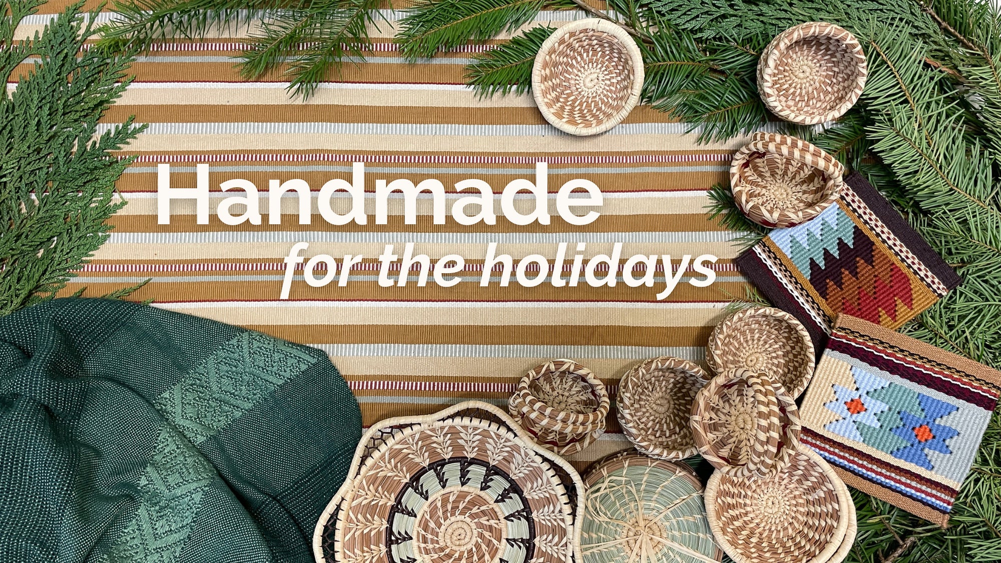 Handmade for the holidays - Overhead view of striped Sand Peine table runner, Brocade shawl in deep green, Margarita basket, Madre Tierra tapestry coasters, and miniature baskets, surrounded by evergreen greenery