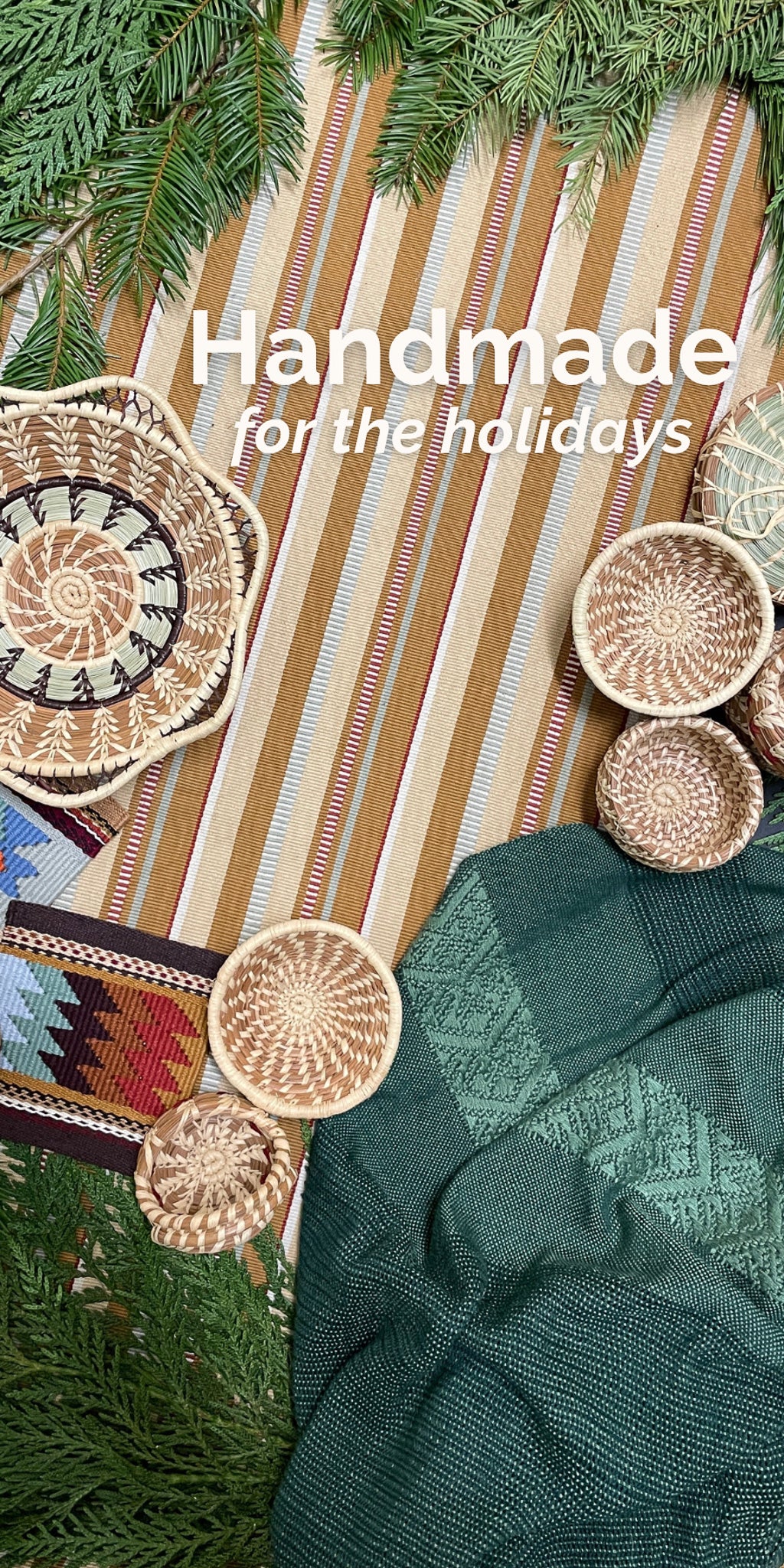 Handmade for the holidays - Overhead view of striped Sand Peine table runner, Brocade shawl in deep green, Margarita basket, Madre Tierra tapestry coasters, and miniature baskets, surrounded by evergreen greenery