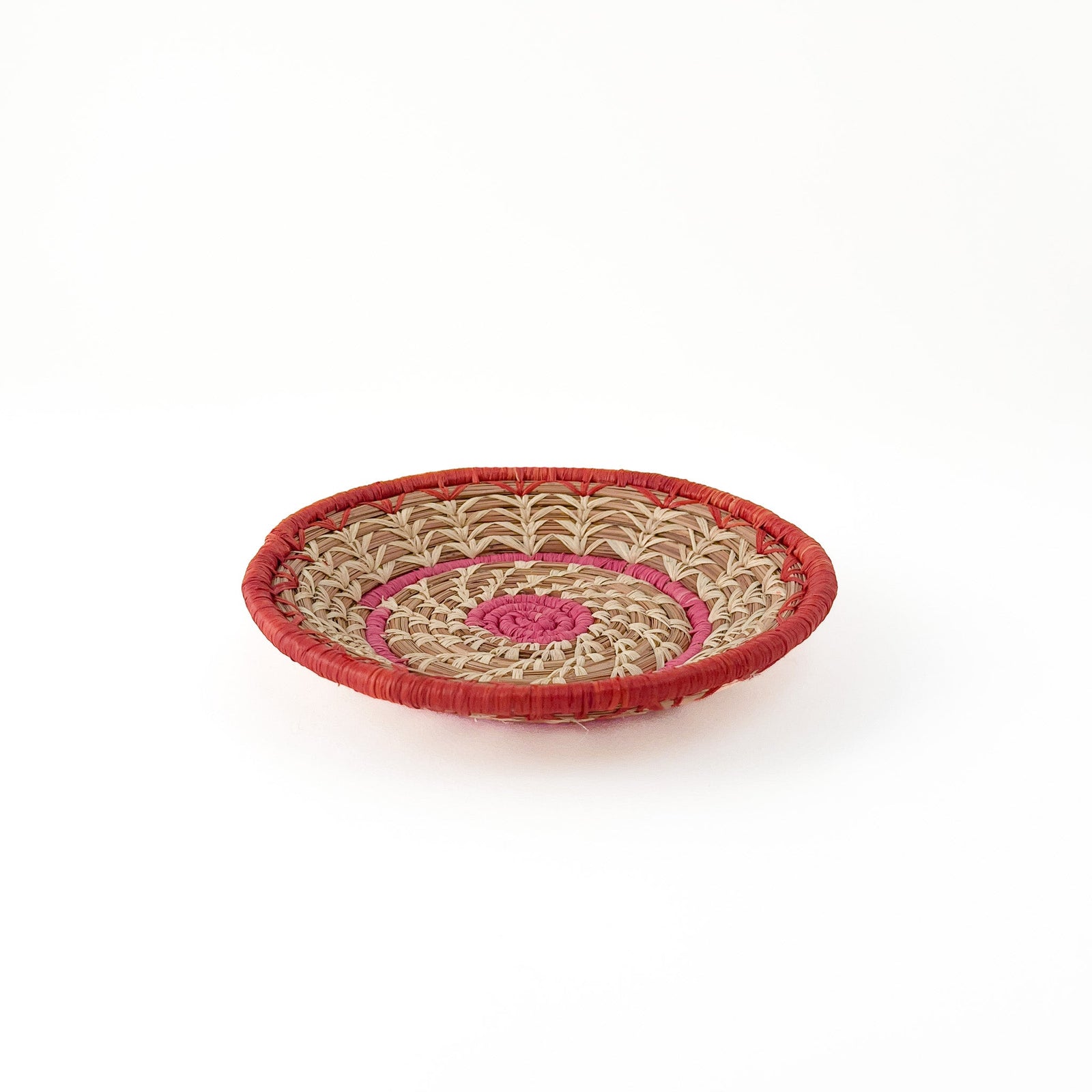 Vibrant pine needle basket with pink and orange stitching and delicate natural raffia accents