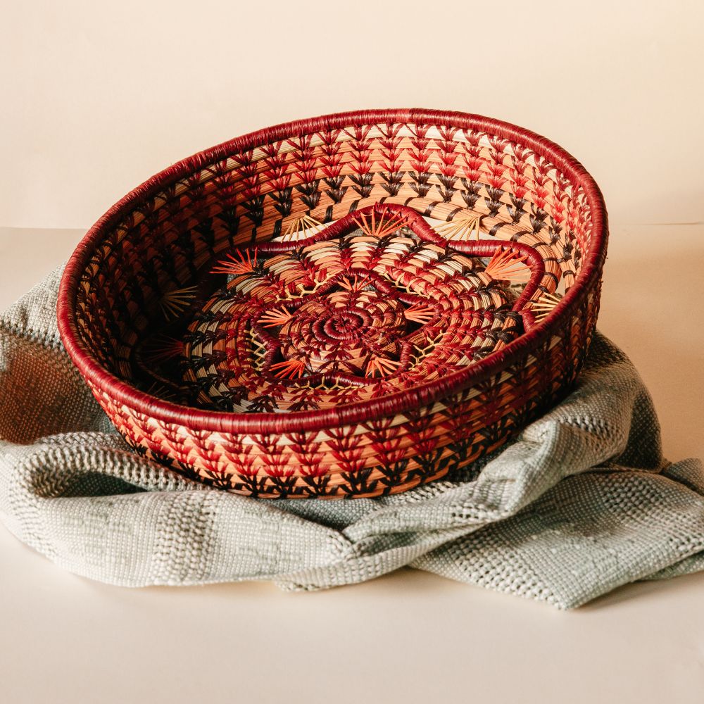 Rosenda Basket in Wine resting on draped sage table runner with soft white background