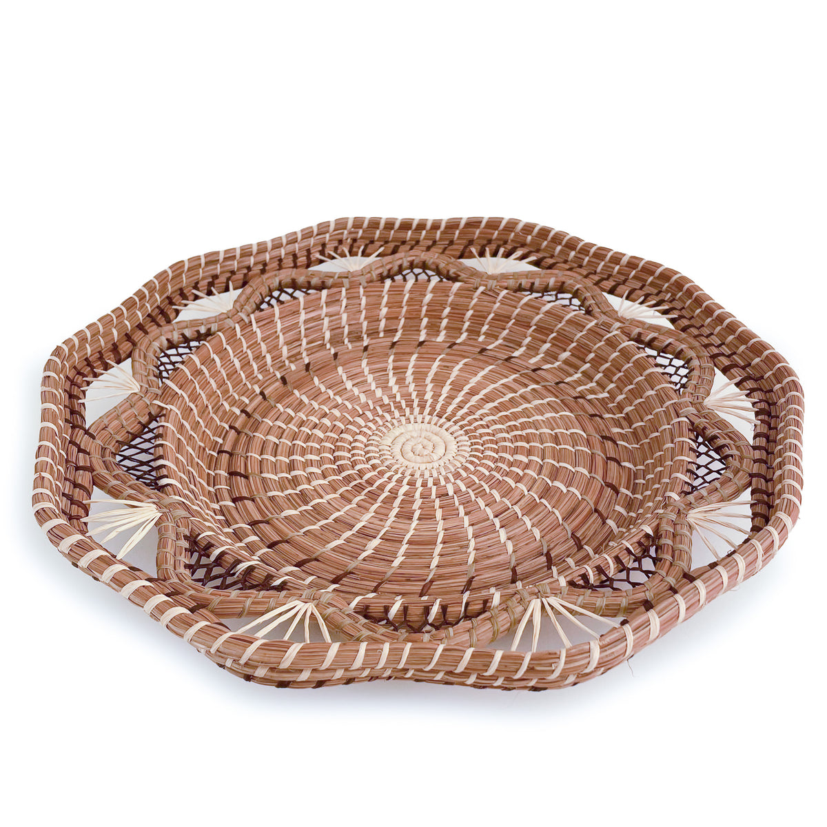 Angled view of woven pine needle Andrea Basket, with scalloped pattern and geometric rim, on white background