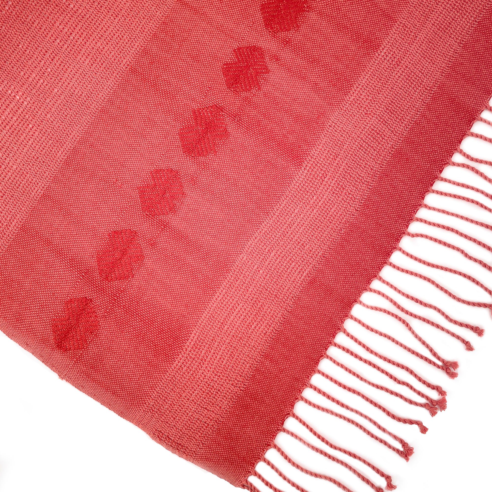 Flatlay photo of coral colored shawl with hand knotted fringe and brocade detail