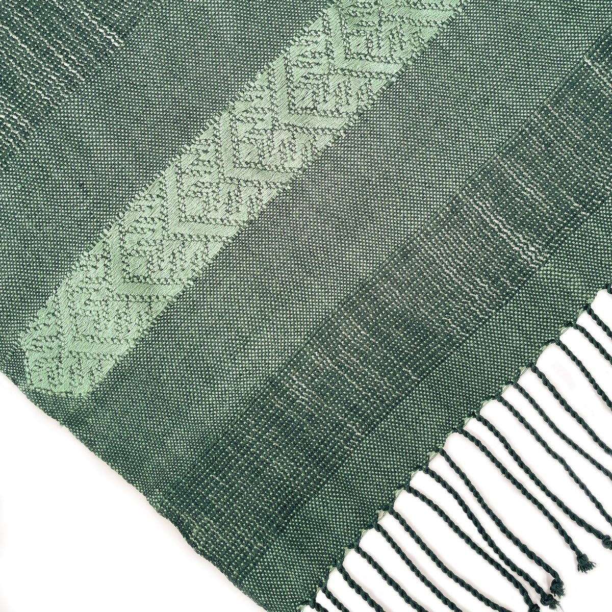 Closeup of green shawl with arrow brocade detail and hand tied fringe