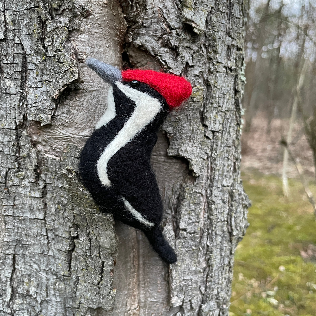 Felted woodpecker against a tree trunk