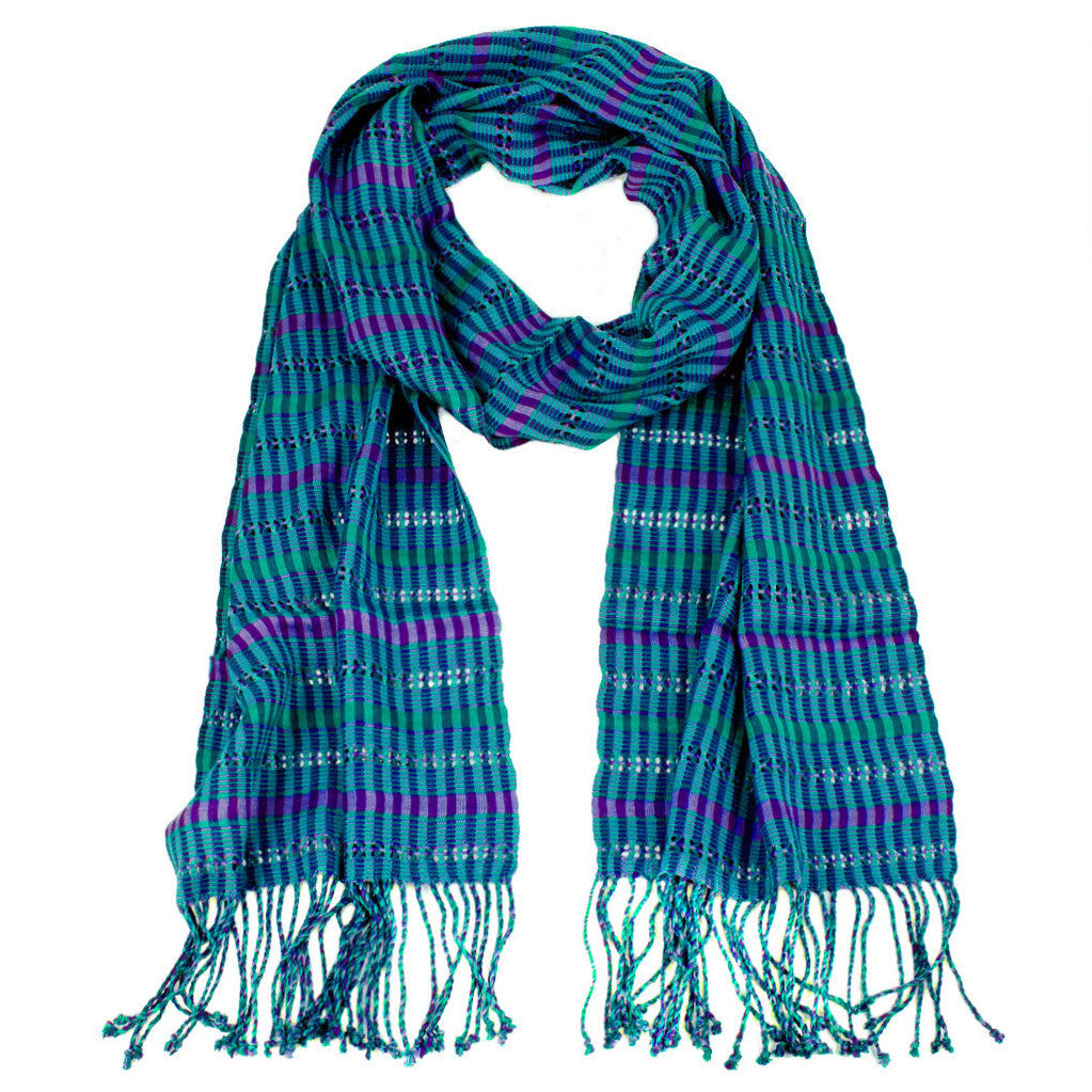 Annabelle Scarf in Cerulean Blue, made from rayon threads in blue, purple, and teal, with twisted fringe. The scarf is laid flat, wrapped with a circle on white background..