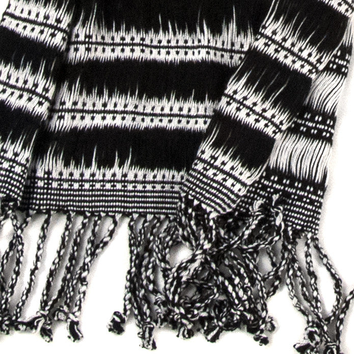 Maya Moonlight Scarf, woven from rayon threads in black and white stripes and patterns, with twisted fringe. The scarf is laid flat, wrapped with a circle on white background.
