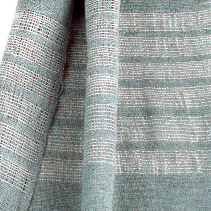 Recycled Denim Scarf, woven from recycled denim threads for a gauzy effect, with fringe. The scarf is laid flat, wrapped with a circle on white background.